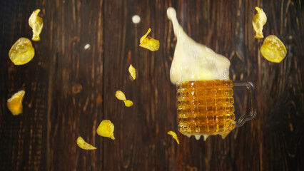 glass of foamy golden cold beer falls down with crisps flakes
