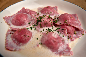 Delicious Plate of Homemade Pink Ravioli Stuffed with Flavorful Filling in Creamy Sauce Garnished with Fresh Herbs, Perfect for Gourmet Dining Experience
