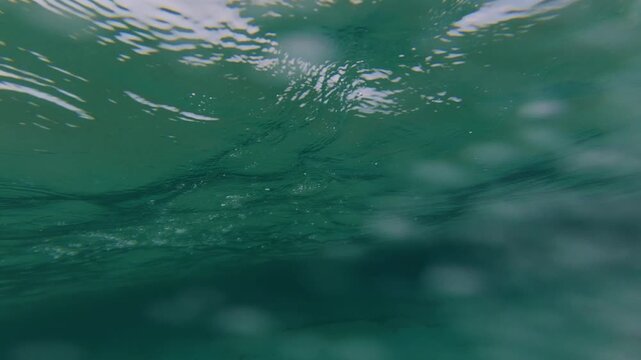 POV of a boy jumping off a rock into the turquoise sea. First-person view of a summer leap into clear water near a rocky beach. Fun, adventure, and nature combined