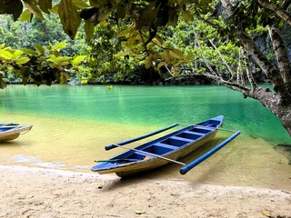 Empty Canoe along side an Emerald River in the Jungle