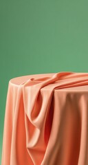 Peach fabric draped over a round table against a mint green background