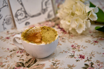 A Beautifully Designed Cup of Coffee Topped with Aromatic Spices and Surrounded by Delicate Flowers on a Floral Tablecloth