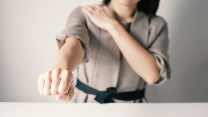 Businesswoman extends her arm and is massaging her shoulder with her hand. Shoulder pain from work fatigue and muscle numbness. Massage and relax muscles.Office syndrome concept