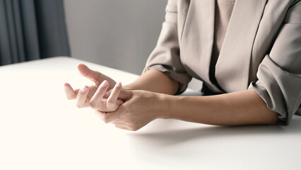 Asian business woman massaging wrist in pain Caused by working on a computer keyboard for a long time, wrist pain and numbness in the wrist. While working at the office