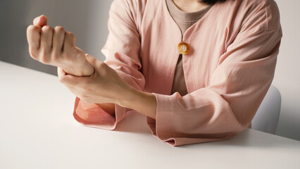 Asian business woman massaging wrist in pain Caused by working on a computer keyboard for a long time, wrist pain and numbness in the wrist. While working at the office