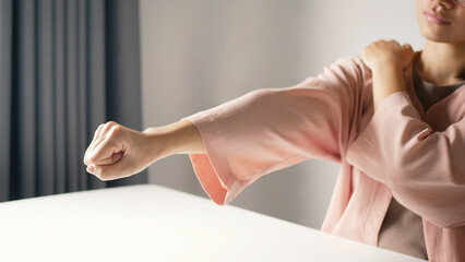 Businesswoman extends her arm and is massaging her shoulder with her hand. Shoulder pain from work fatigue and muscle numbness. Massage and relax muscles.Office syndrome concept