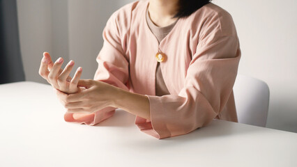 Asian business woman massaging wrist in pain Caused by working on a computer keyboard for a long time, wrist pain and numbness in the wrist. While working at the office