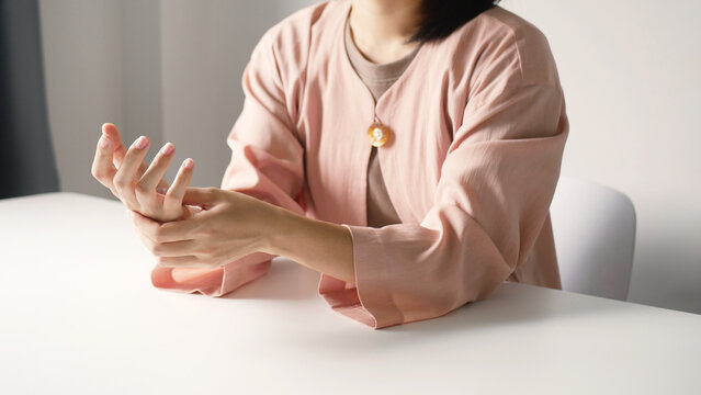 Asian business woman massaging wrist in pain Caused by working on a computer keyboard for a long time, wrist pain and numbness in the wrist. While working at the office