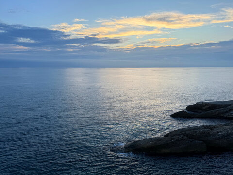 Evening ocean, rocks and dark sky clouds.