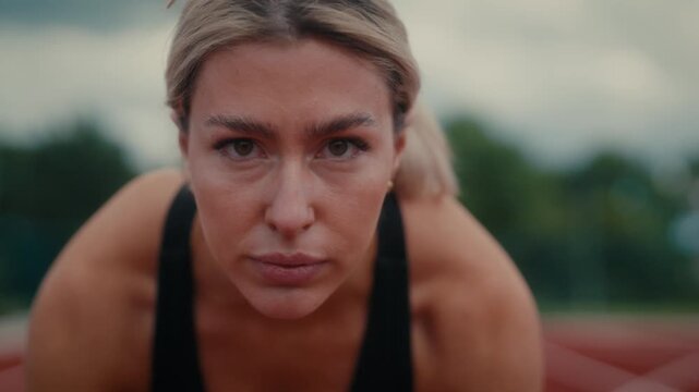 Portrait, a close-up of a woman with a focused and determined expression, suggesting she is prepared for a physical activity or competition. 