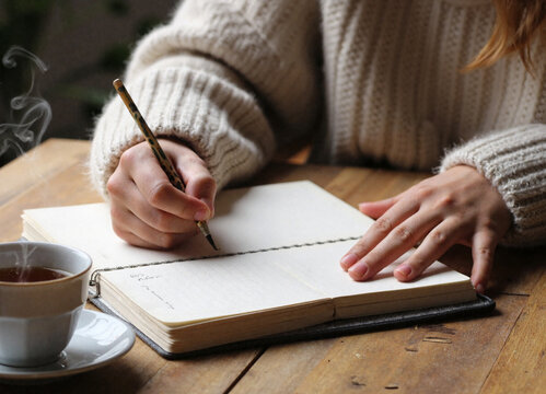 young woman writing in a book about wellness tips