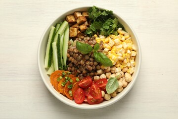 Healthy vegetarian food. Delicious Buddha bowl with lentils, tofu, chickpeas and vegetables on light wooden table, top view