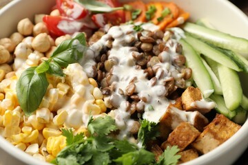 Healthy vegetarian food. Delicious Buddha bowl lentils, tofu, chickpeas, vegetables and sauce as background, closeup