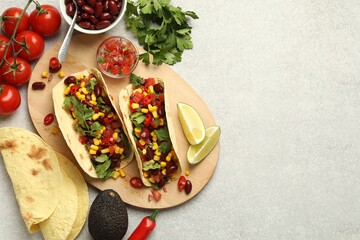 Tasty vegetarian tacos and ingredients on light grey table, flat lay. Space for text