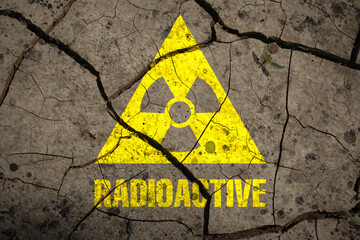 Yellow radioactive sign on cracked dry earth, top view. Radiological pollution