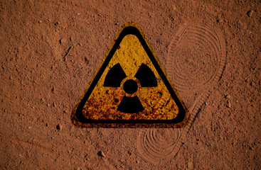 Radioactive sign on brown ground with shoes track, top view. Radiological pollution