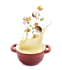 Croutons and mushrooms falling into bowl of soup against white background