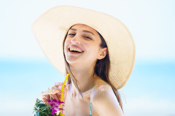 Beautiful caucasian woman smiles to camera while holds a pineapple by the beach.
