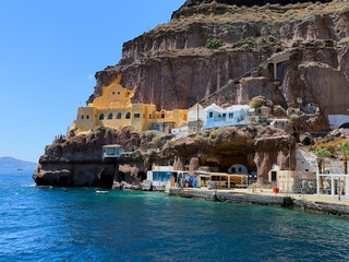 Vivid yellow and blue houses built into the rocky cliffside above the sea in Santorini, Greece