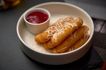 Deliciously Crispy Fried Dough Sticks Dusted with Grated Cheese Served with a Side of Sweet Sauce for a Flavorful Snack Experience