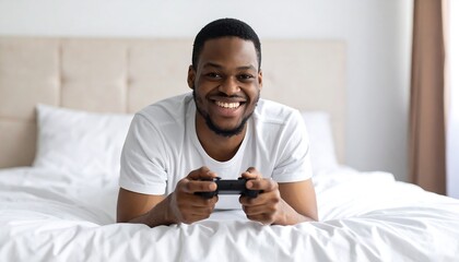 A smiling man plays video games on a bed