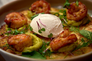 Deliciously Garnished Shrimp Dish with Creamy Topping on Savory Base Surrounded by Fresh Herbs and Microgreens