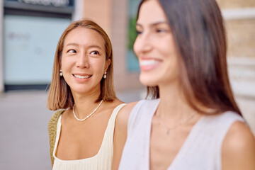 Two female friends are enjoying a walk together in an urban setting, sharing a moment of happiness and connection