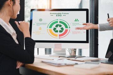 Sustainable future ESG concept with businesswoman discussing environmental, social, and governance strategy at office, computer screen showing recycle symbol and infographic, teamwork, planning