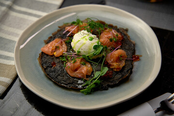 Delicious Gourmet Dish Featuring Black Crepe with Smoked Salmon, Fresh Herbs, and Creamy Dollop of Whipped Cheese on a Stylish Plate