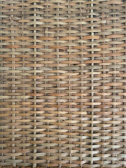 This close-up image shows a tightly woven rattan or synthetic wicker pattern in shades of brown and black, commonly used in outdoor furniture. The texture is geometric, uniform, and durable in appeara