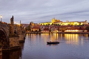 Obraz premium Night scenery of Charles Bridge, with the majestic Prague Castle and St. Vitus Cathedral in background at moody dusk and reflections of lights on the water of Vltava River, in Old Town Prague, Czech