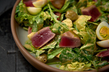 A vibrant and nutritious salad featuring fresh greens, seared tuna, hard-boiled eggs, and olives, delivering a delightful and healthy meal option.