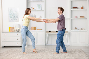 Fototapeta premium Happy young couple dancing together at home