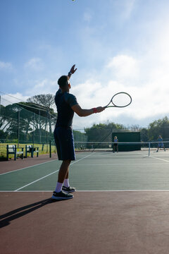 Diverse tennis opponents wearing sportswear competing on public park tennis court with net