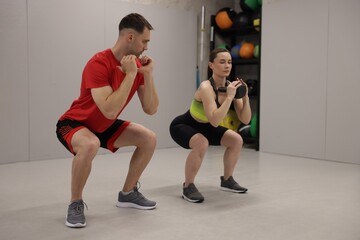 Obraz premium Young woman exercising with kettlebell with professional personal trainer in gym