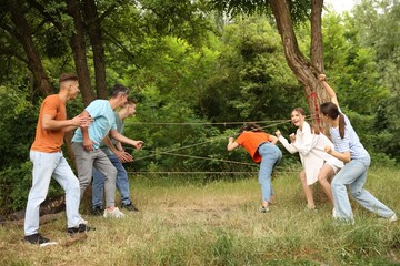 Fototapeta premium Team building. Group of happy people playing spider web game outdoors