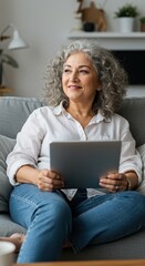 Contented Senior Woman Enjoying Tablet At Home On The Couch Thinking Actively