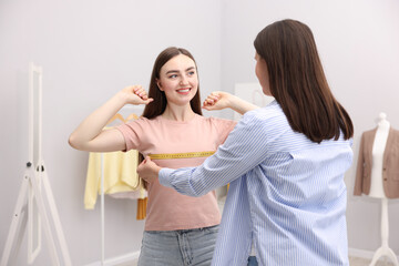 Tailor measuring woman's chest with tape in atelier