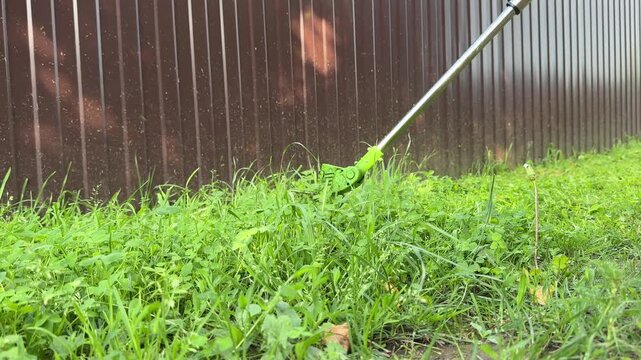 Lawn mower at work. Man cutting weed using a special equipment. Gardener mows grass using a professional trimmer.