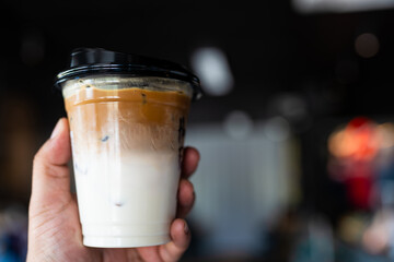 Iced latte in plastic cup on man hand.
