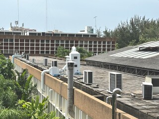 An array of air conditioning and ventilation units on a tropical rooftop in Thailand, showing the...