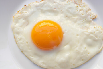 Fried egg on white dish close up