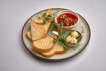 Deliciously Presented Bread and Unique Red Spread with Toppings, Accompanied by Creamy Delights on a Stylish Plate, Perfect for a Satisfying Snack Experience