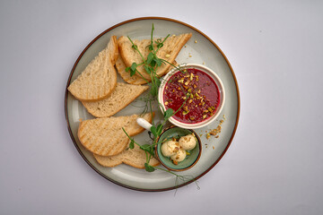 A Delicious Plate Featuring Toasted Bread, Creamy Butter, and Vibrant Red Spread Topped with Nuts and Fresh Greens for a Flavorful Snack Experience