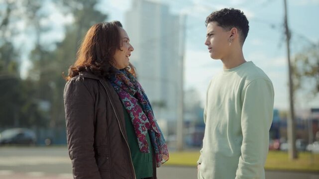 Mother and teenage son talking outdoors in the city
