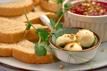 A Beautifully Arranged Plate Featuring Fresh Bread, Creamy Cheese Balls, Salty Nuts, and a Tasty Fruit Spread Garnished with Greenery for a Delightful Culinary Experience
