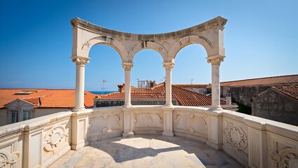 Elegant white stone balcony with ornate carvings and arched colonnade overlooking terracotta rooftops and blue sky
