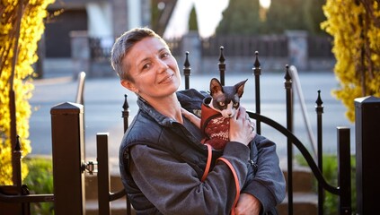 Woman Walking Outdoors with Canadian Sphynx Cat in Arms