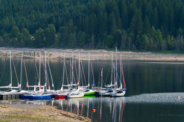 yachts near pier on the tranquil lake with forest coast