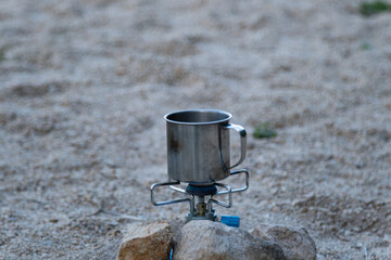 a mug on the camping gas burner hided in stones